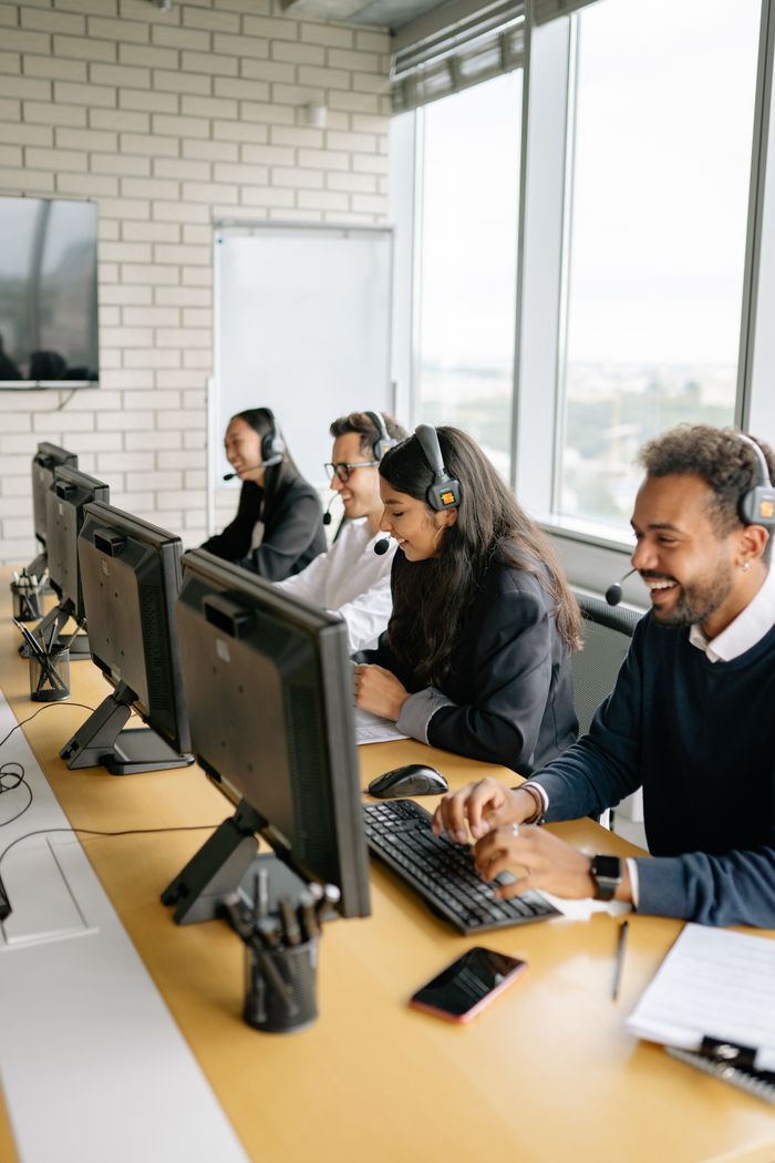 Services-03 A diverse group of call center employees working together at desks in a modern office.